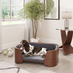 Elegant Jual Furnishings pet bed in walnut wood finish with plush gray cushioning, featuring a relaxed spaniel dog lounging in a stylish modern living space, complemented by a matching curved walnut lamp table for a cohesive design